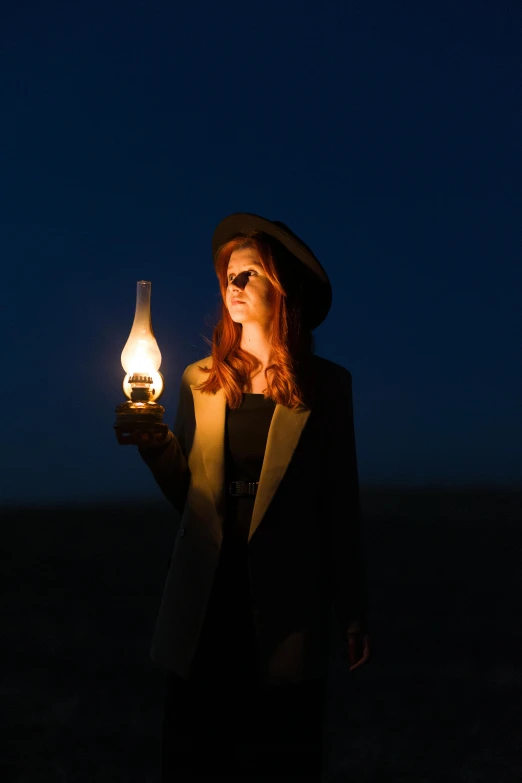 a woman wearing sunglasses and holding up a lit lantern