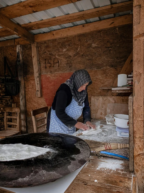 a woman in a hut is making flour