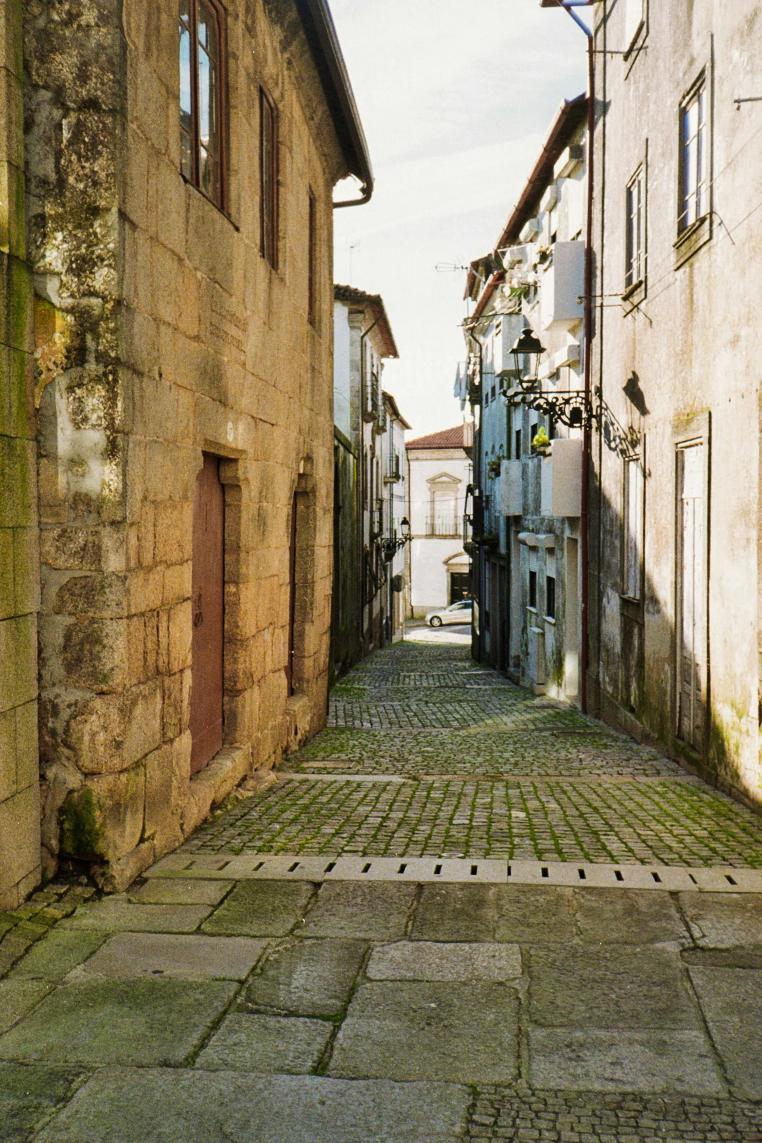 narrow street with old buildings, a telephone tower, and tiled cobblestone walkway