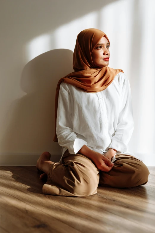 a woman with a tan scarf sits on the floor