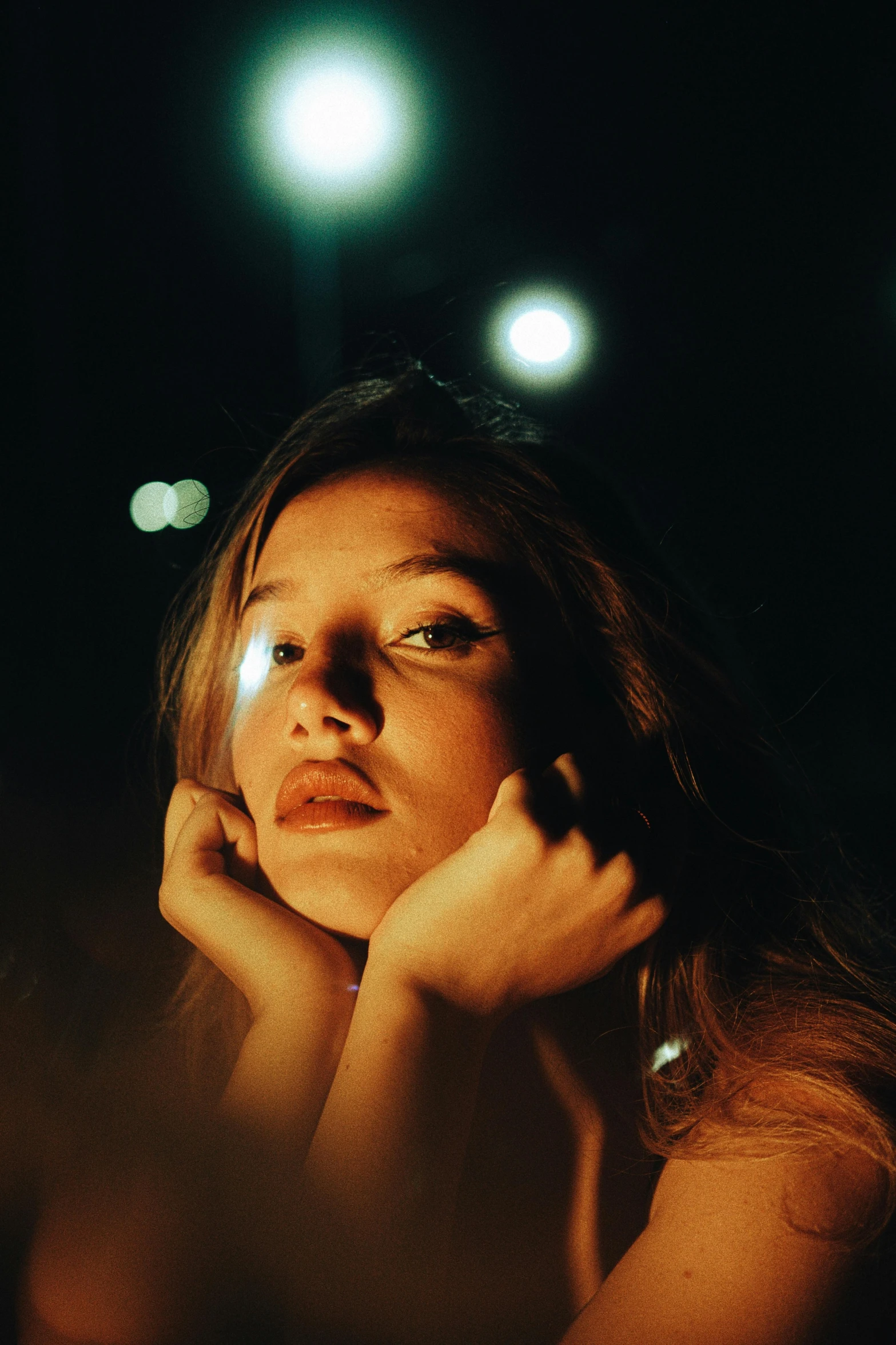 a woman standing at night with her hands to her face