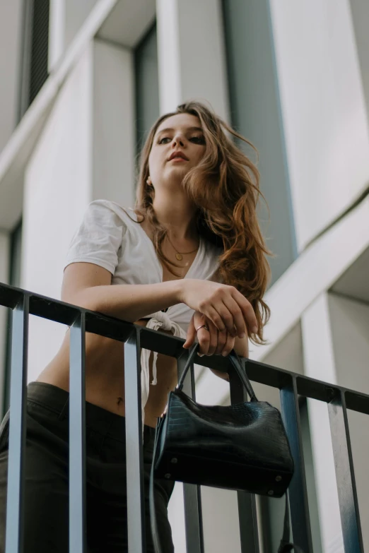 young woman standing on balcony with her handbag and staring up