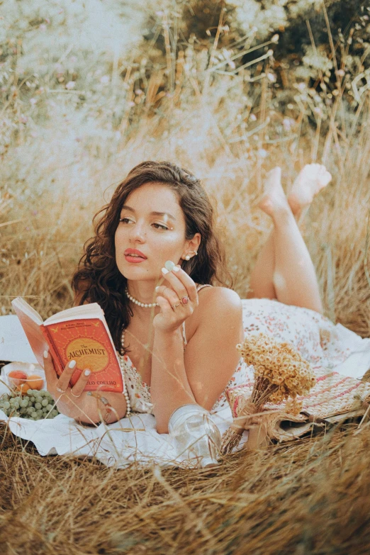 woman reading an orange book on a blanket