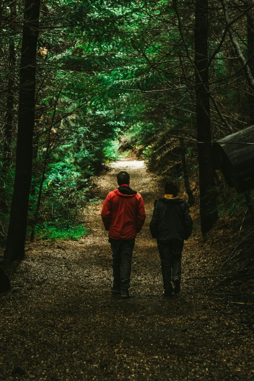 two people walking down a path in the woods