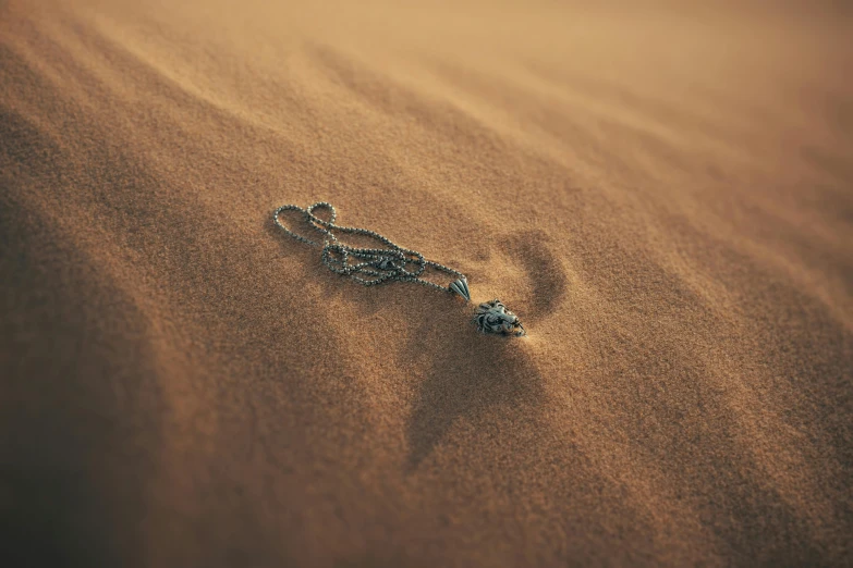 a necklace is laying on a sandy beach