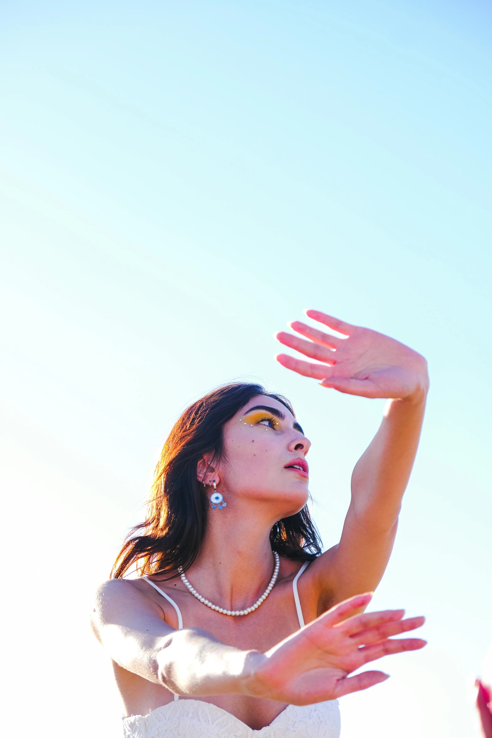 a woman that is wearing a dress and reaching up to catch a frisbee