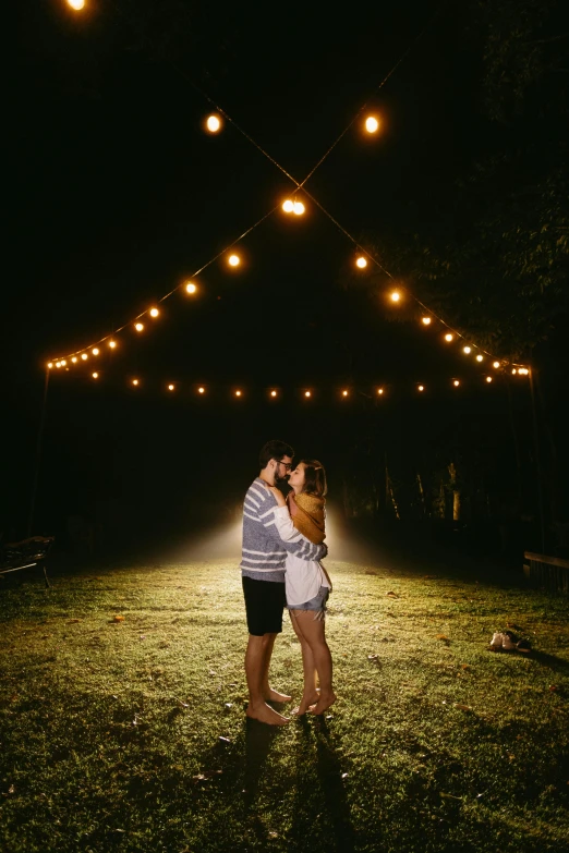 couple kissing under overhead lights at night