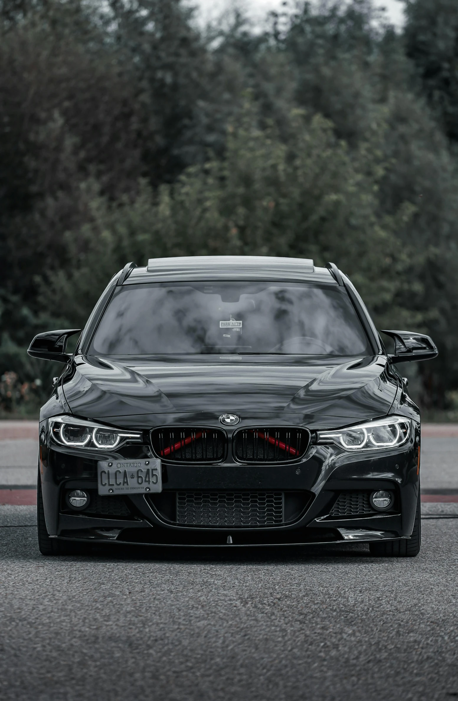 a dark black car parked next to a forest