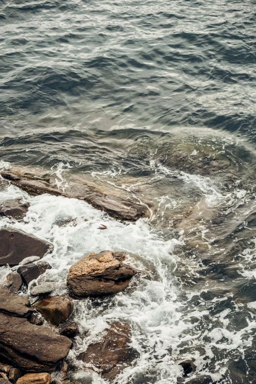 some rocks are in the water by the shore