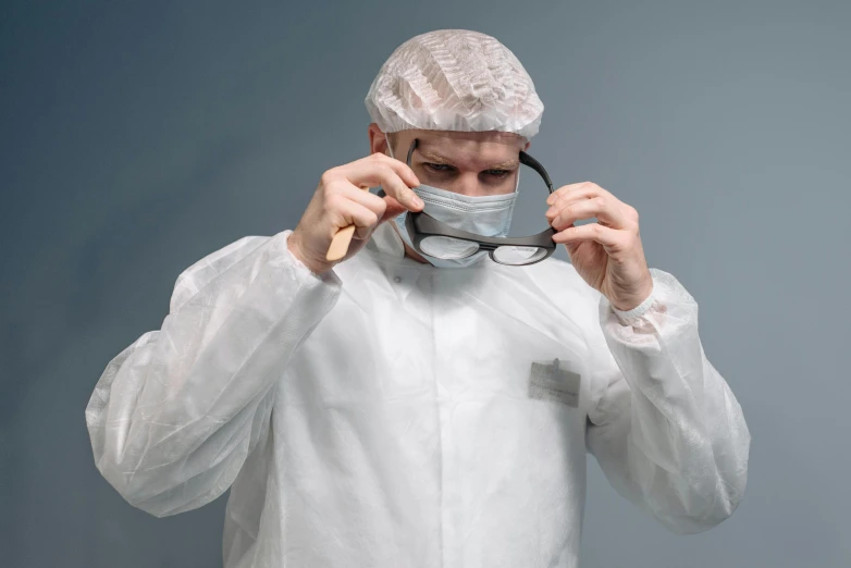 a man with a face mask and glasses holds up a magnifying glass