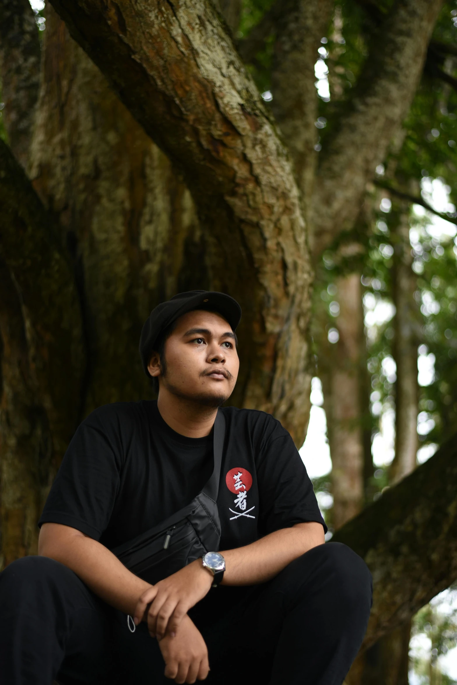 a young man sitting on a bench in front of a tree