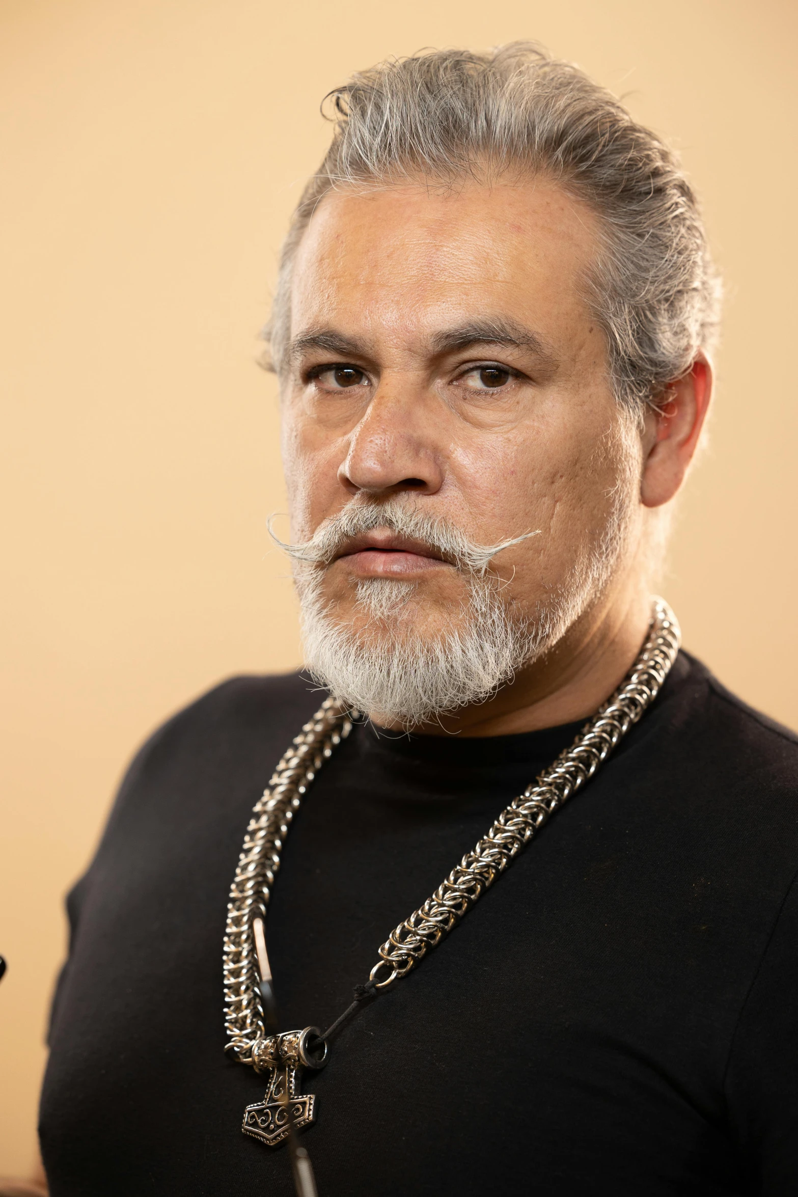 a man is wearing a cross necklace and posing