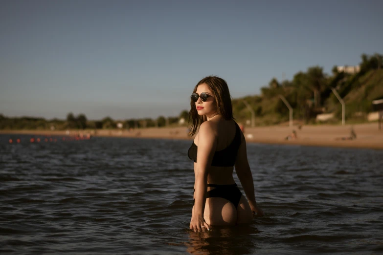 girl wearing sunglasses standing in the water of the ocean