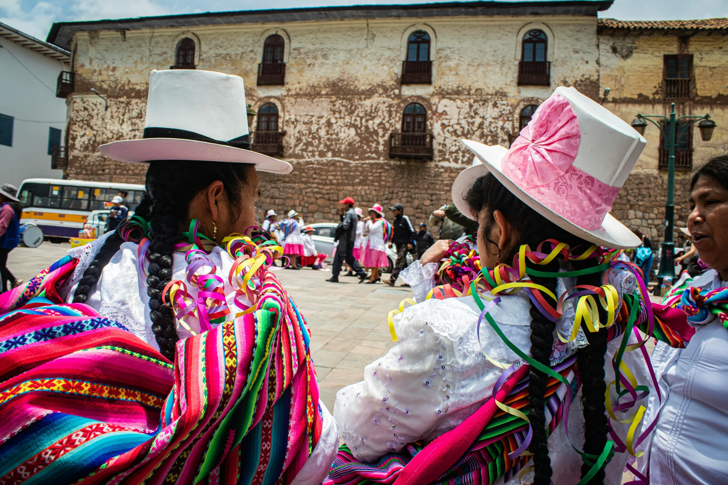 a group of women standing around each other wearing hats