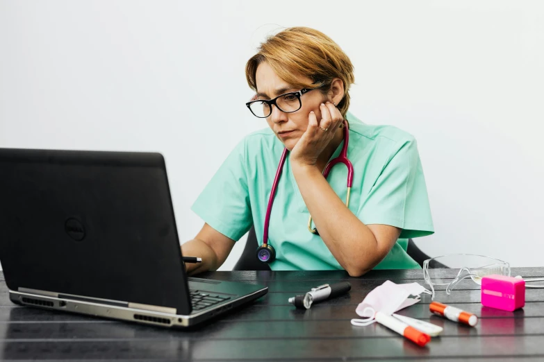 a nurse looks at her laptop with a stethoscope on