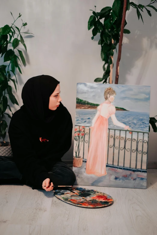 a woman kneeling on the ground near a painting