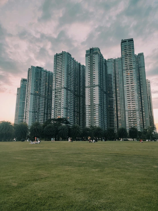 a large park with many people and tall buildings behind it