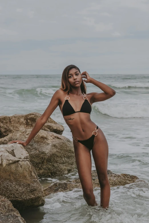 a woman in a bikini and sunglasses walking into the water