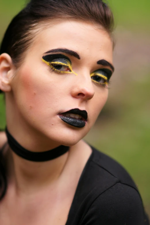 there is a girl with black makeup and yellow lipstick on her lips
