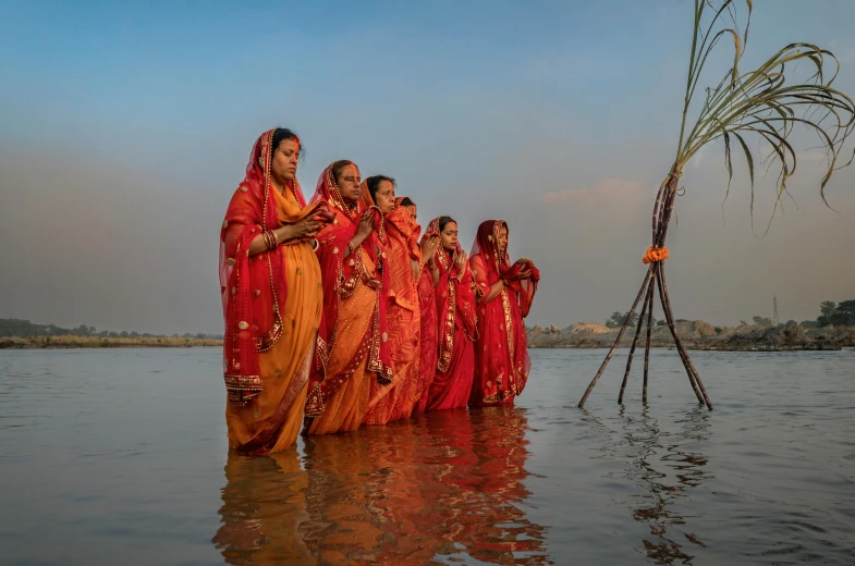 a group of women standing on the beach dressed in saris