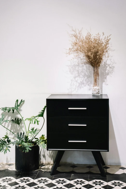 a small black cabinet with a flower in it