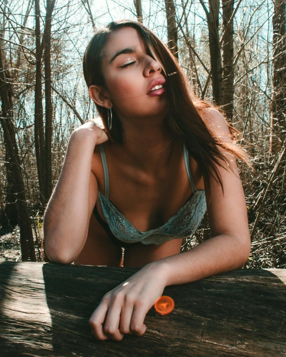 a young woman in a bathing suit sitting on a log