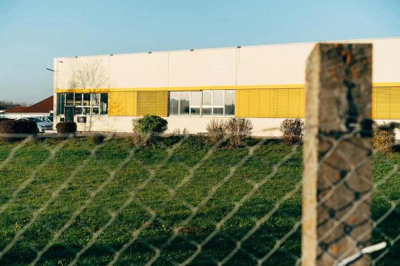 a building with a fence surrounding it, as viewed from across the field