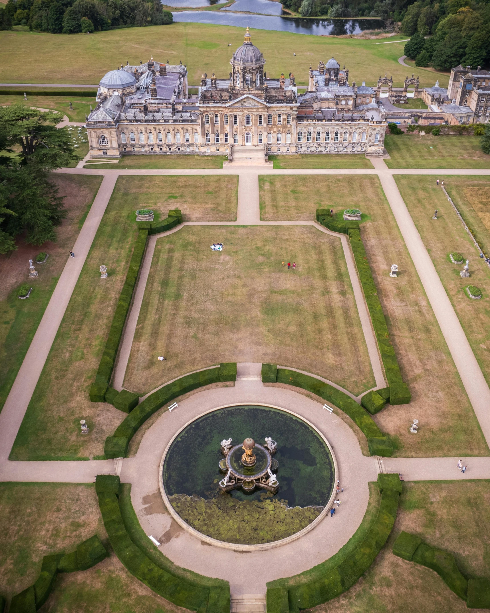 the aerial view of a palace with gardens, fountains and buildings