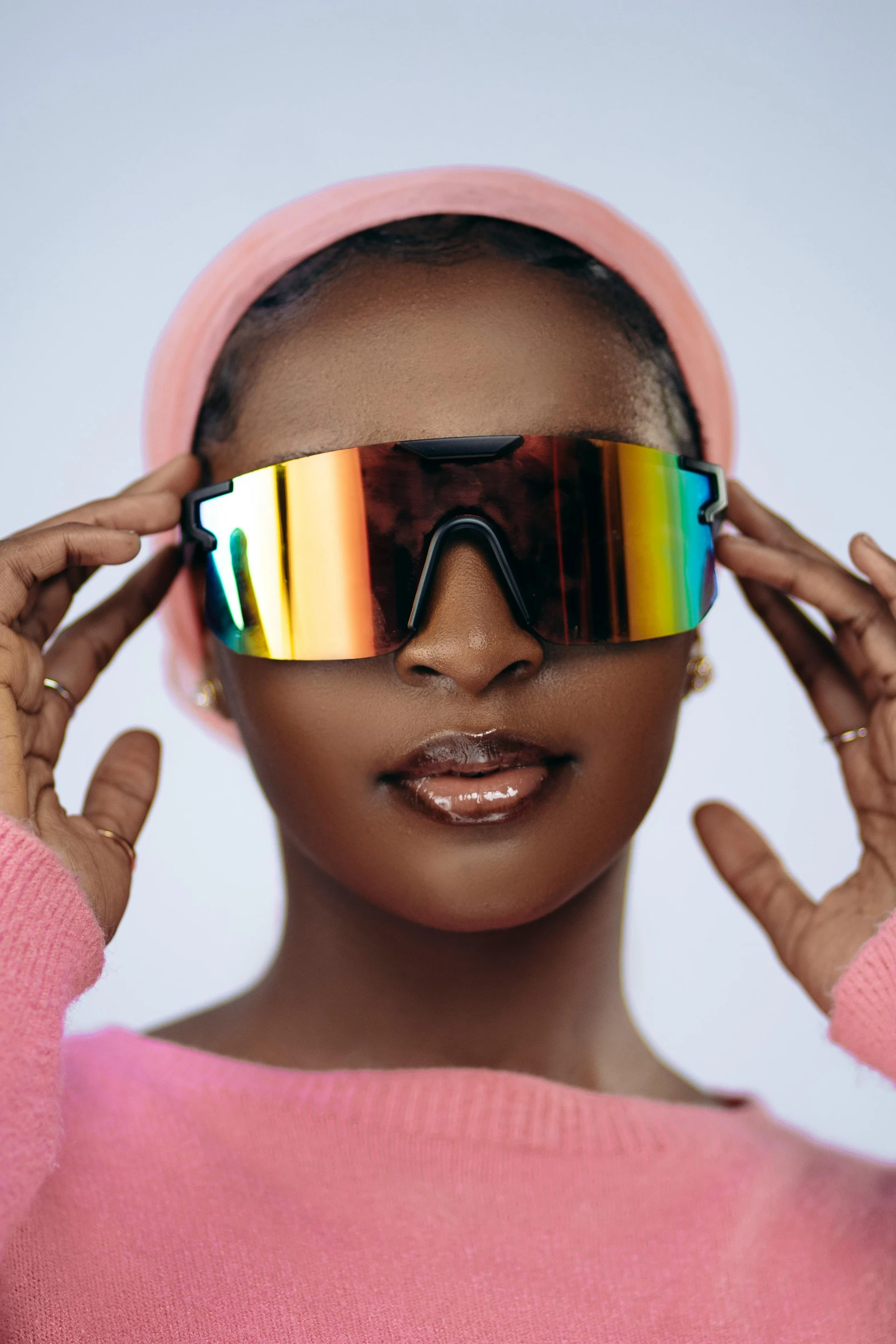 a black woman in a pink sweater wearing a pair of shiny glasses