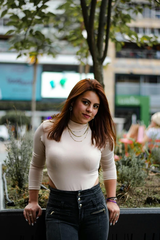 an attractive woman in a tight top posing by a fence