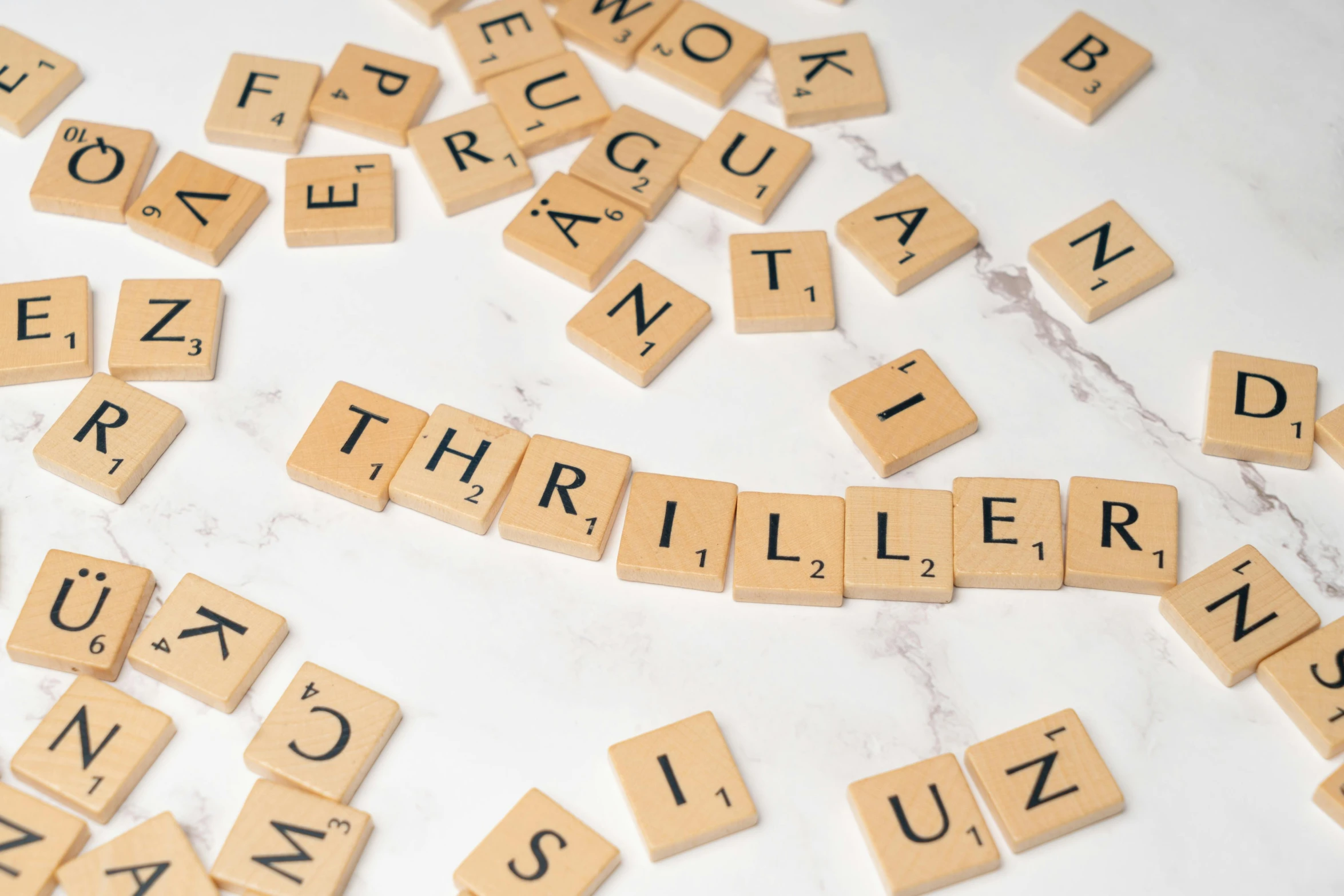 scrabbled wooden letters arranged across the letter tiles