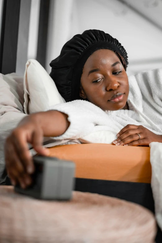 the woman is laying down and holding a remote control