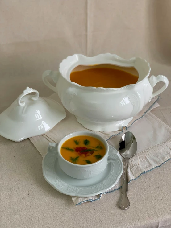 there is soup in a white bowl next to some creamers