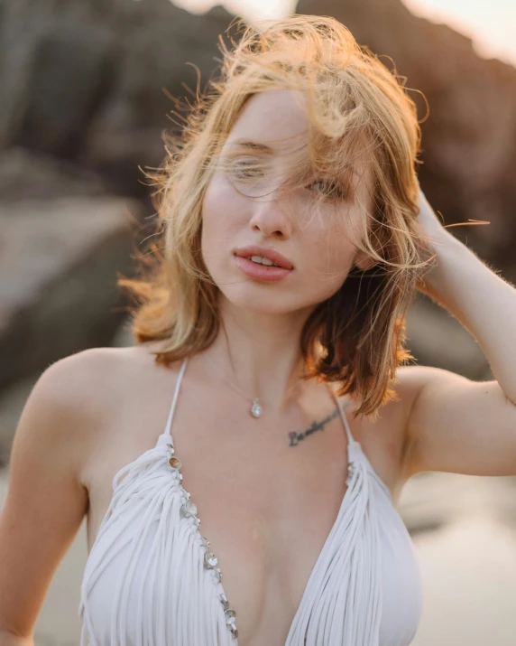 a woman posing on the beach wearing her hair in the wind