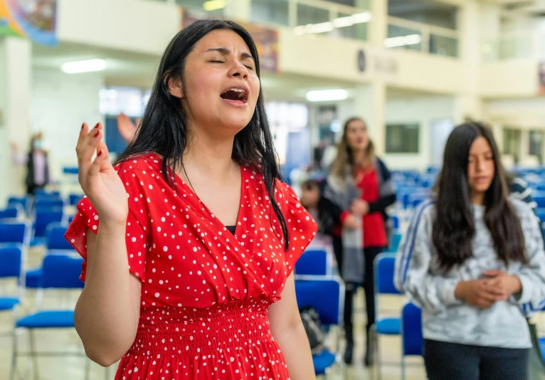 a woman is singing at a ceremony with other people