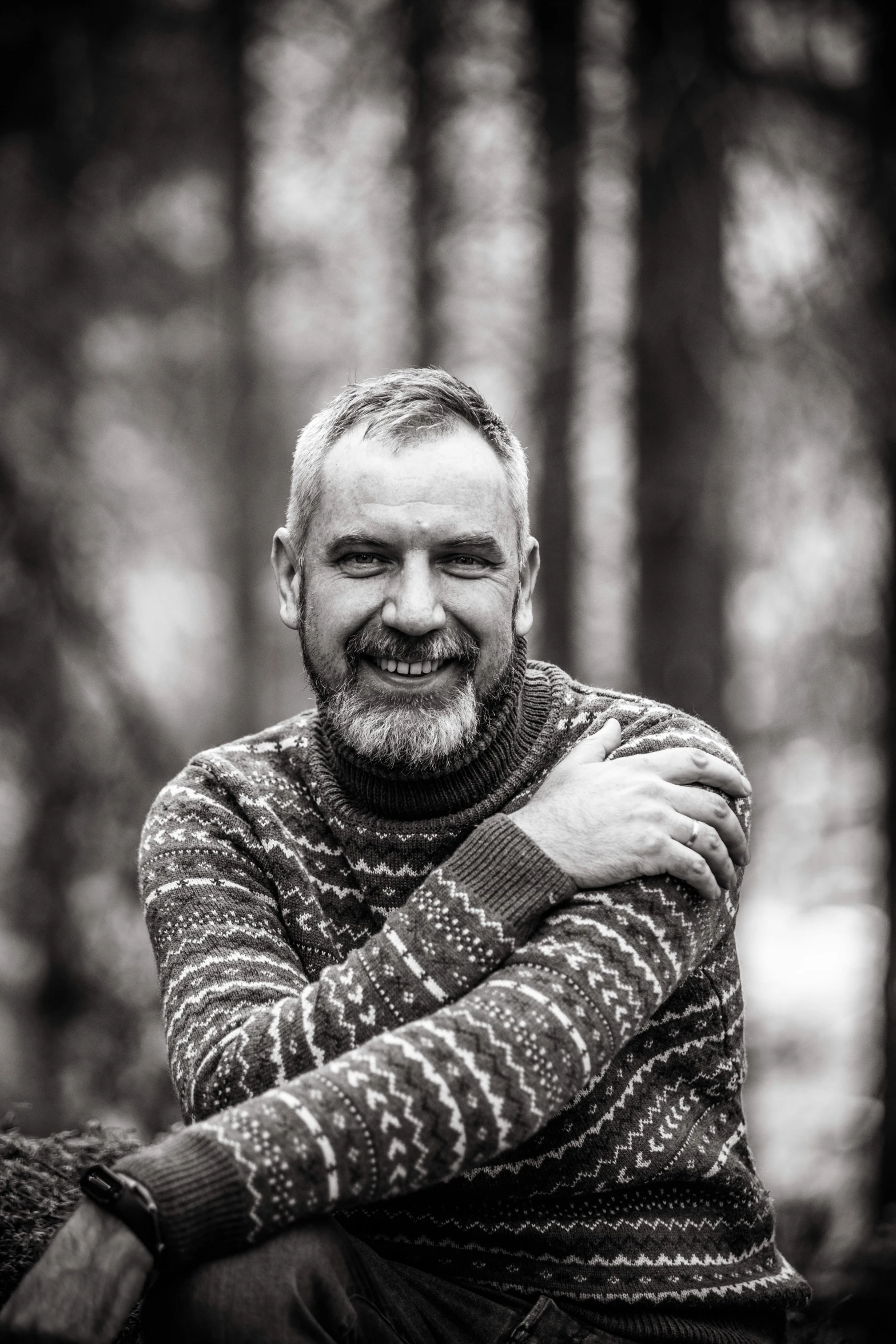 a man sitting in front of a forest with a blanket on his back