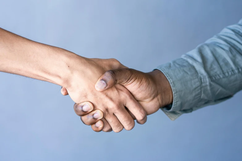 two people shaking hands over a white surface