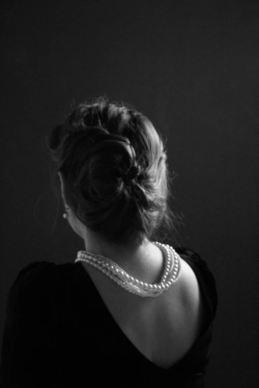 woman in a black top with a pearl necklace