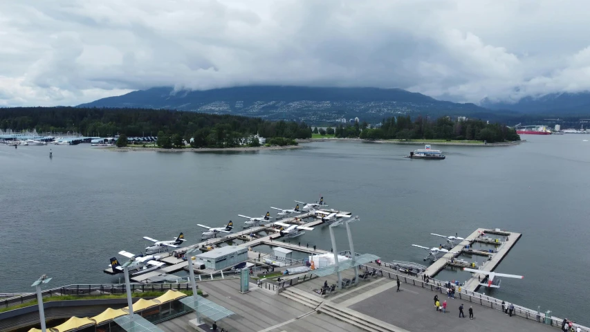 people walking to an airport beside the water with a plane parked in it