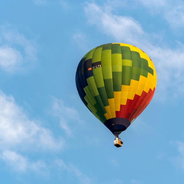a yellow and green balloon flying in a clear blue sky