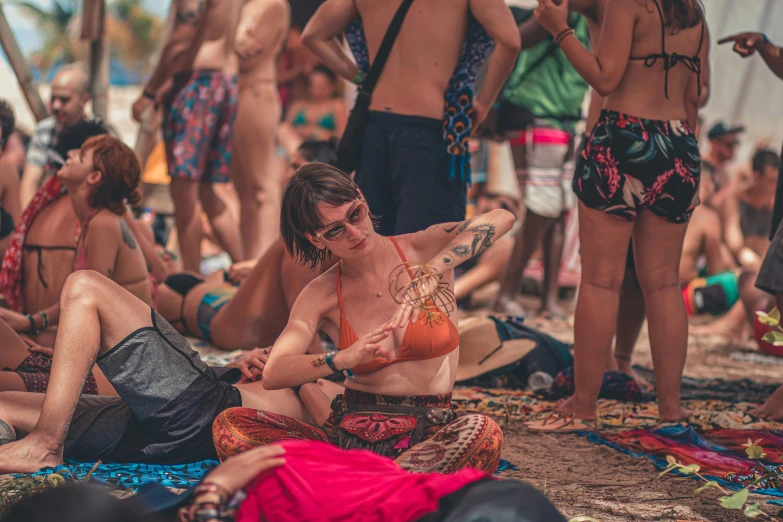 a woman wearing an orange bikini top on the beach with other people