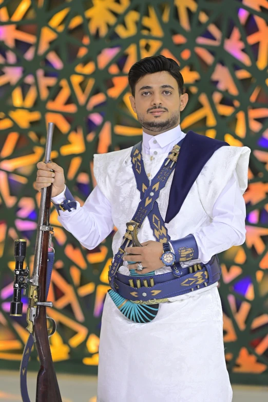 a male in a white apron holds a sgun and rifle