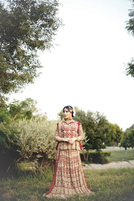 an indian woman in traditional clothing standing under the shade of a tree