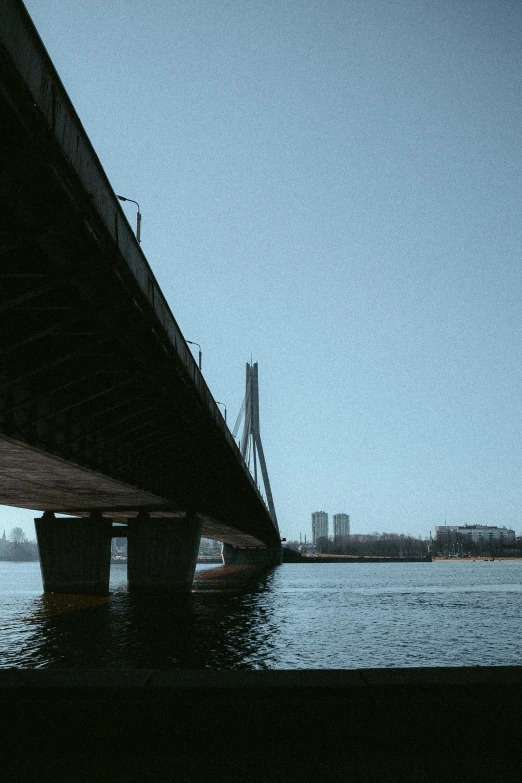 the underside of a bridge at dusk with a view of water underneath