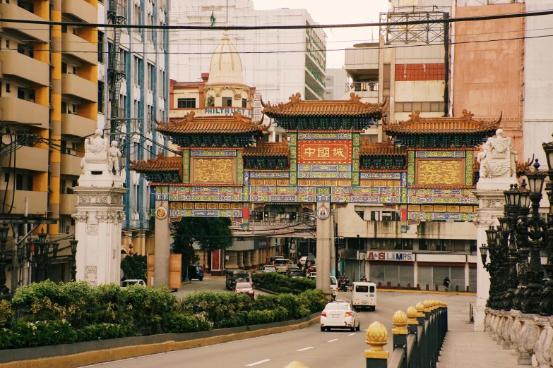 an oriental - styled gate is above a street lined with buildings