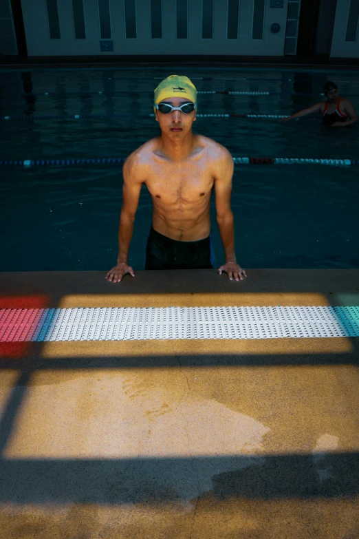 a man sitting next to a swimming pool in his swimming cap