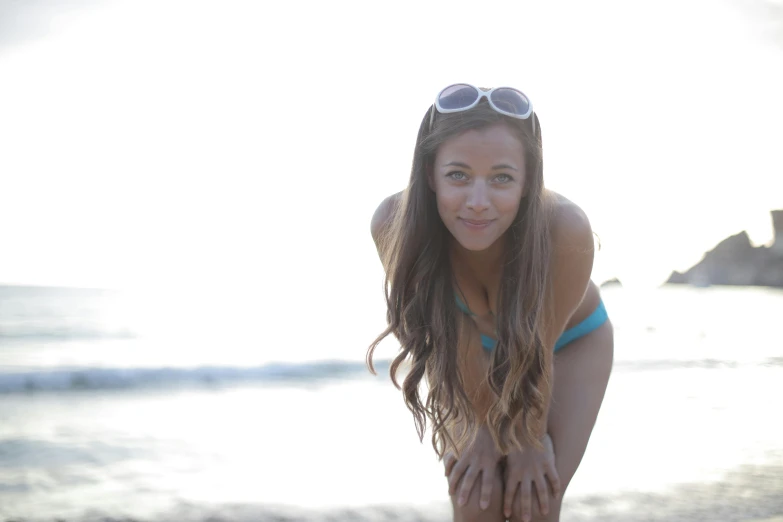 a woman wearing sunglasses posing on a beach