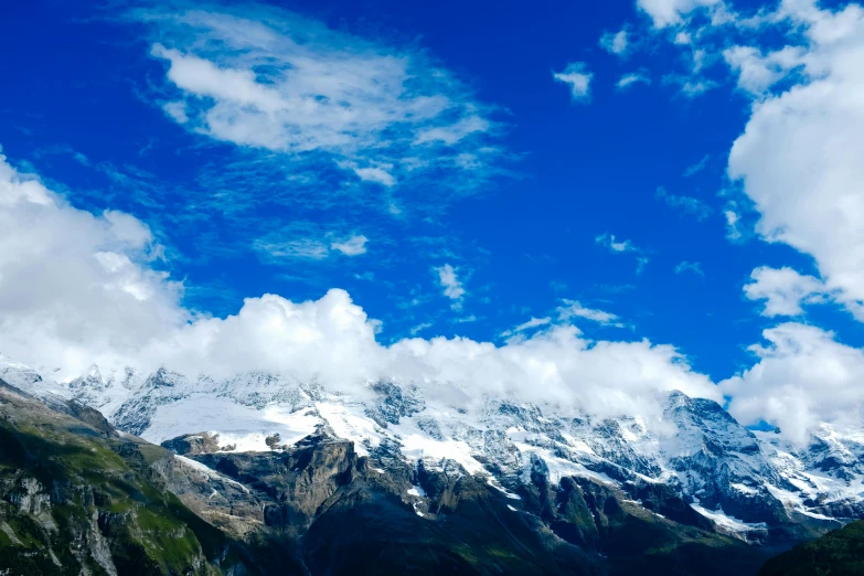 the clouds in the sky are rolling over the mountain tops