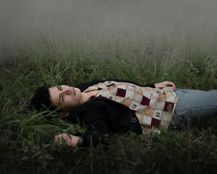 a young man laying down in the grass