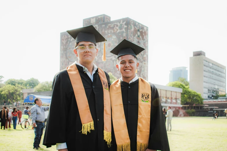 a couple of men standing next to each other in graduation caps and gowns